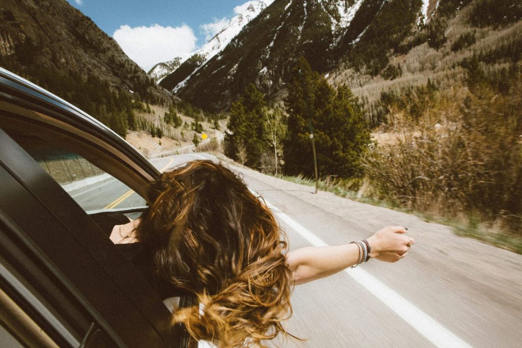 woman in car | neurofeedback therapy in denver, co | neurofeedback therapy in littleton, co | neurofeedback therapy | neurofeedback therapy for anxiety | adhd neurofeedback | neurofeedback and anxiety | 80127 | 80128 | 80124 Image of a woman hanging out of a car window driving down a highway through the mountains. Learn to effectively cope with your ADHD symptoms with the help of neurofeedback therapy in Denver, CO.
