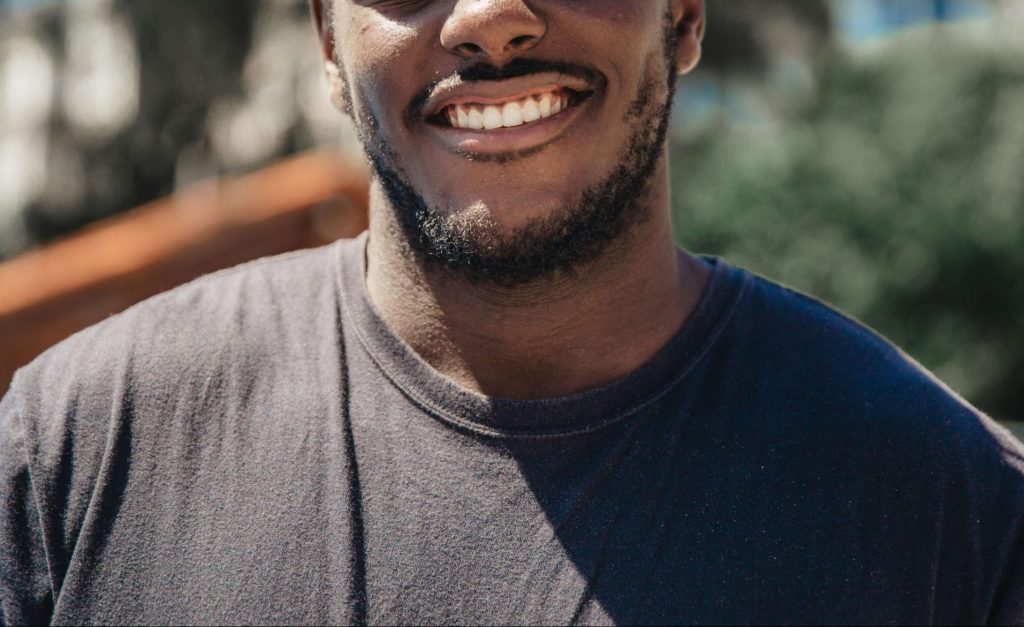man in black shirt | neurofeedback therapy in denver, co | neurofeedback therapy in littleton, co | neurofeedback therapy | neurofeedback therapy for anxiety | adhd neurofeedback | neurofeedback and anxiety | 80125 | 80121 | 80110 Image of a smiling man wearing a black shirt standing outside on a sunny day. Learn to manage your TBI with the help of neurofeedback therapy in Denver, CO.