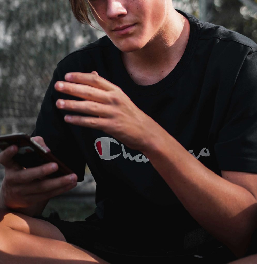 teen with phone | teen counseling in littleton, co | teen counseling in englewood, co | teen counseling in denver, co | teen therapist | therapy for teens | 80127 | 80128 | 80124 Image of a teen boy sitting on the ground outside holding a cell phone. Learn the benefits of teen counseling in Littleton, CO and how it can help your teen!