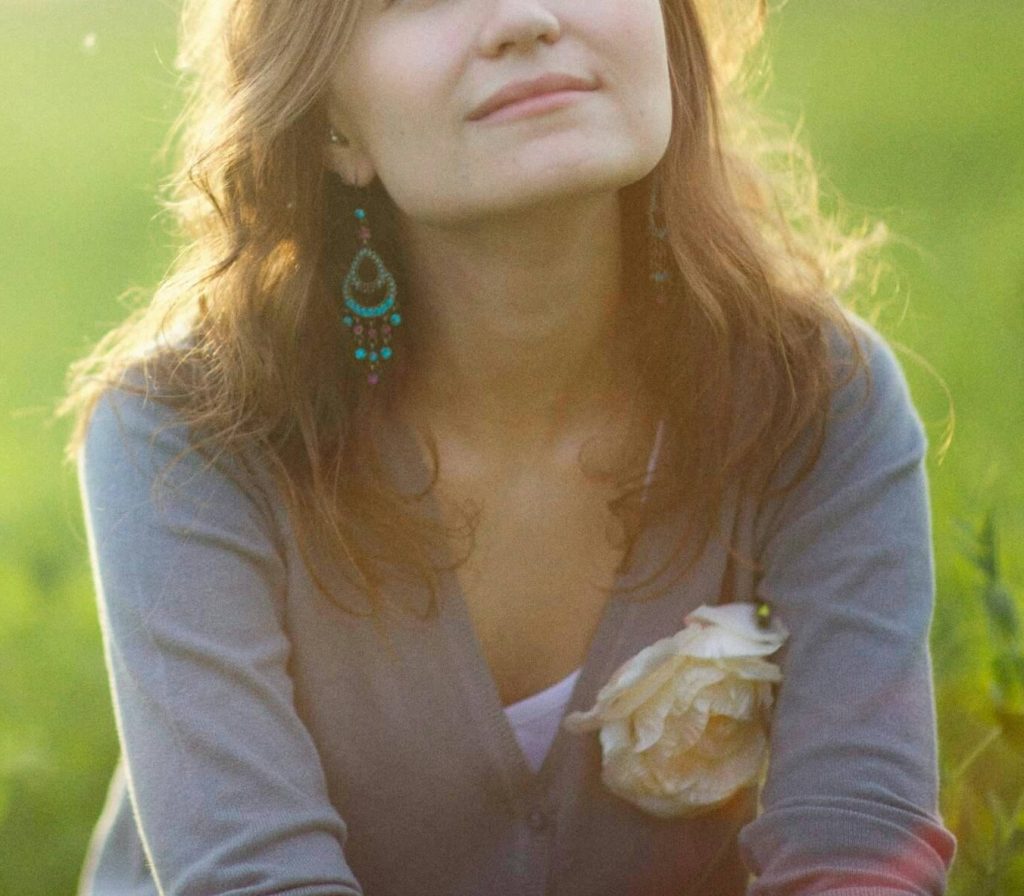 smiling woman | neurofeedback therapy for denver, co | neurofeedback therapist in denver, co | neurofeedback for anxiety | neurofeedback for adhd | neurofeedback near me | 80125 | 80121 | 80110 Image of a young woman sitting in the grass smiling as the sun shines on her. Overcome your mental health challenges with the help of neurofeedback therapy in Denver, CO.