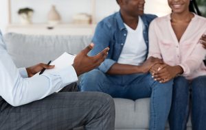 smiling couple | family therapy in englewood, co | family counseling in englewood, co | family therapy in littleton, co | 80125 | 80121 | 80110 A couple smiles while sitting across from a person with a clipboard. This could represent the support a family therapist in Englewood, CO can offer. Search for family therapy in Englewood, CO to learn more about online therapy in Colorado and other services.