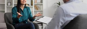 smiling woman | eft therapist in littleton, co | anxiety therapy in Englewood, co | anxiety therapist in englewood, co | 80125 | 80121 | 80110 A woman smiles while gesturing with her hands while sitting across from a man with a clipboard. Search for an EFT therapist in Littleton, CO and how they can offer support via anxiety therapy in Englewood, CO. Learn more about emotional freedom technique in Greenwood Village, CO.
