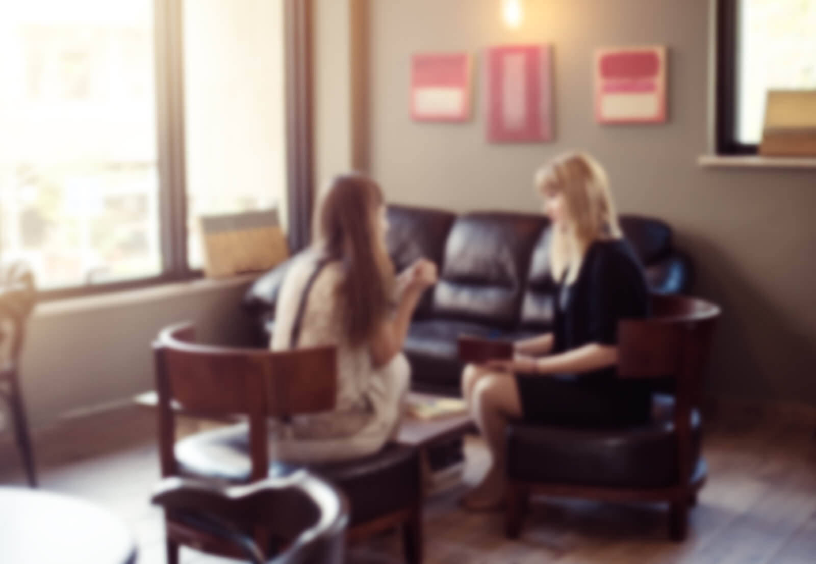 therapy office | therapist in hampden, co | neurofeedback denver | adhd testing in denver | Denver, CO Two women sit in a cozy, softly lit therapy office, engaged in conversation. This welcoming space reflects the environment clients experience when receiving co-parenting counseling, neurofeedback Denver services, or online therapy in Denver, CO. Compassionate care from a therapist in Hampden, CO is just a conversation away.