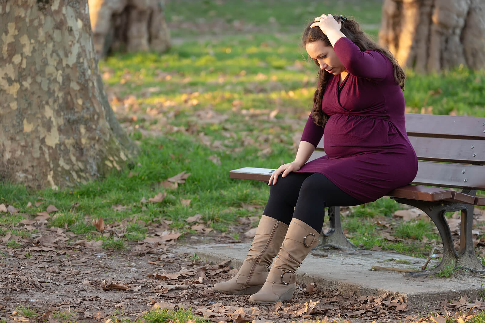 anxious woman | maternal mental health therapist | postpartum depression therapist near me | postpartum depression counseling in englewood, co | greenwood village, co | englewood, co | denver, co Anxious pregnant person sitting alone on a park bench, showing the emotional weight many moms carry and how therapy for moms, a skilled maternal mental health therapist, postpartum depression counseling in englewood, co, and a postpartum depression therapist near me can offer relief.